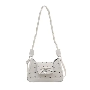 Chic off-white underarm bag with bow pattern and metal heart pendant detail