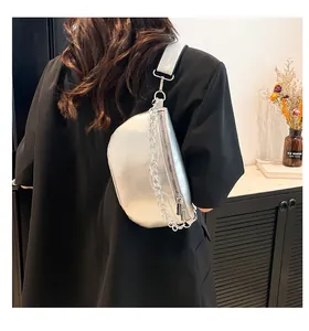 Détail du sac banane argenté avec chaîne épaisse et large bandoulière en tissu