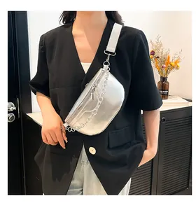 Silver metallic fanny pack with chunky chain detail worn by a model in black blazer