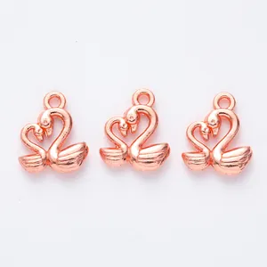Détail de trois pendentifs cygne en forme de cœur en or rose pour création de bijoux DIY