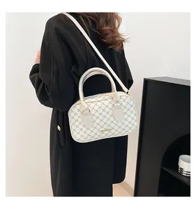 Mannequin portant un sac Boston crème à motif géométrique doré et bandoulière réglable