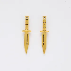 Detailed view of two vintage gold alloy dagger pendants with decorative textured handles