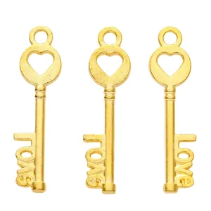 Three vintage gold alloy key pendants with heart cutouts and Love engraving on white background