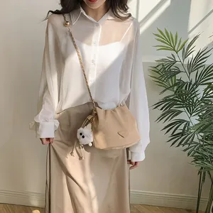 Elegant beige bucket bag with gold chain strap and cute plush charm on model