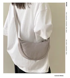 Detail of light gray nylon crescent bag showing soft fabric texture and wide shoulder strap