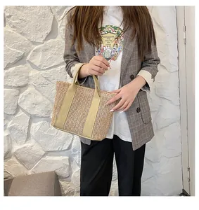 Detail of hand-woven straw tote bag with khaki ribbon handles for summer beach travel