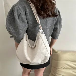 White corduroy large capacity hobo shoulder bag with plush pendant on female model