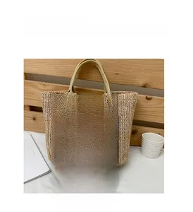 Detail of woven straw shoulder bag with durable canvas handles and natural texture