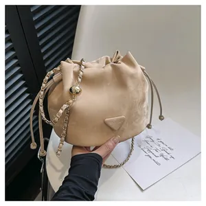 Bolso tipo cubo de ante beige con cadena dorada y detalle decorativo de bola de metal