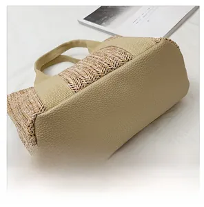Detail of woven straw tote bag with khaki leather trim and durable canvas handles