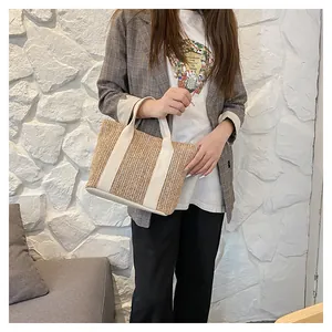 Detail of the woven straw tote bag featuring creamy canvas straps and V-pattern texture