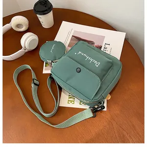 Detail view of retro green canvas crossbody bag with small round coin purse on wooden table