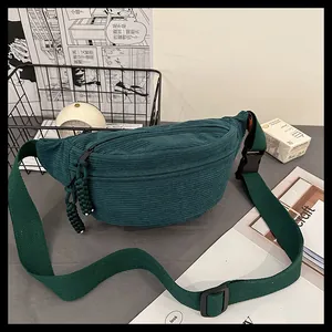 Detailed close-up of dark green corduroy texture and woven zipper pull on a waist bag