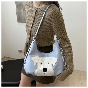 Close-up of light blue crossbody bag with a cute white plush puppy dog patch detail