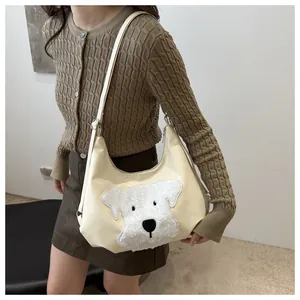 Close-up of cream shoulder bag featuring cute plush cartoon dog patch and silver buckle