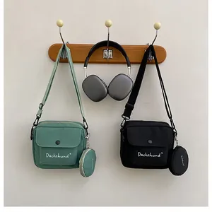 Detail view of nylon crossbody bags in green and black with matching round coin pouches