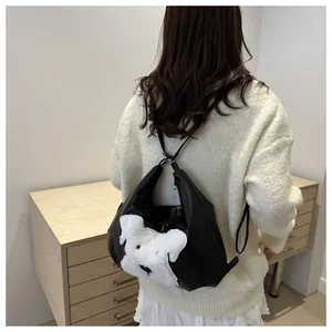 Detail of black PU leather tote bag with white plush dog patch on a minimalist background