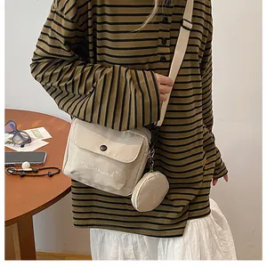 Detail of beige canvas crossbody bag featuring embroidered Dachshund text and a mini coin purse