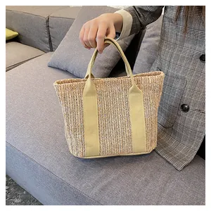 Detail of hand-woven straw tote bag with herringbone pattern and sturdy textile handles