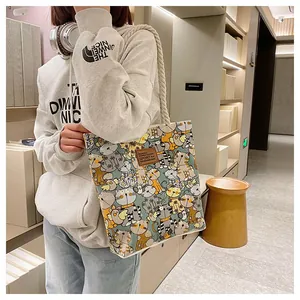 Detail view of canvas tote bag featuring cute cartoon cat patterns and leather patch