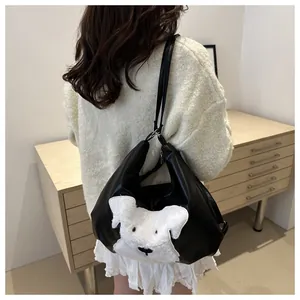 Model wearing a black leather tote bag featuring a white plush dog motif in a home setting