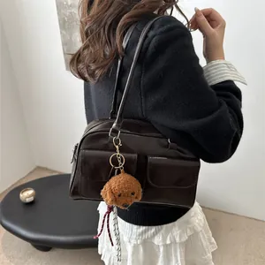 Bolso de hombro vintage marrón oscuro con múltiples bolsillos y oso en una modelo