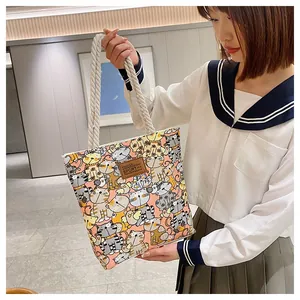 Detail of cartoon cat print canvas tote bag with white rope handles and sport leather patch