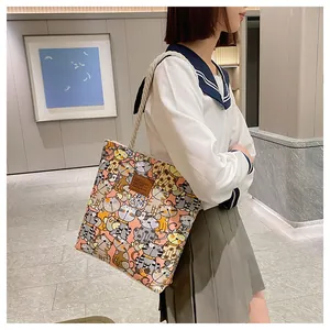 Close-up of a canvas tote bag featuring colorful cartoon cat patterns and leather patch