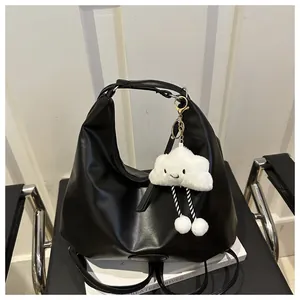 Detail of black PU leather tote bag featuring a cute white cloud plush pendant accessory
