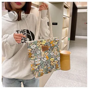 Detail of canvas tote bag featuring colorful cat patterns and durable rope handles