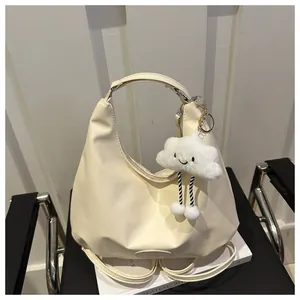 Detail of cream crescent tote bag featuring soft PU leather and plush cloud charm on magazine