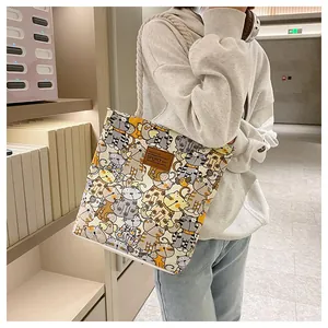 Detail of cartoon cat print canvas tote featuring a brown leather patch and rope handles