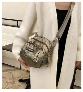 Detail of metallic quilted crossbody bag with adjustable strap and multiple zipper pockets