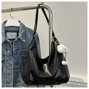 Chic black hobo tote bag in soft leather with a cute white cloud plush charm