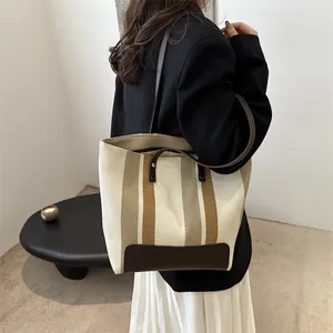 Striped woven canvas tote bag with brown leather straps shown in a modern interior setting