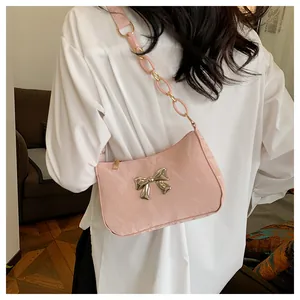 Vista de detalle del bolso rosa de hombro con hebilla de lazo plateado y cadena acrílica