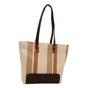 Vertical striped canvas tote bag with brown faux leather handles and rivet accents
