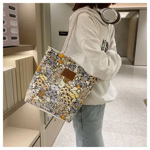 Close-up of canvas tote bag with cartoon cat patterns and leather logo patch detail