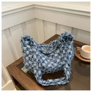 Détail du sac à bandoulière en denim à damier bleu avec bords effilochés dans un café