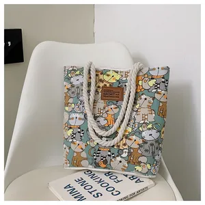 Close-up of canvas tote bag featuring thick rope handles and printed cat illustrations