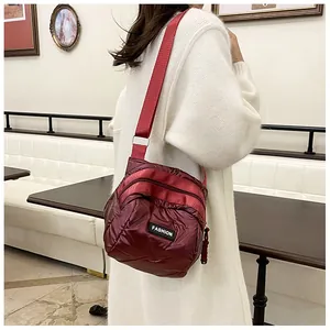 Detail of burgundy quilted nylon crossbody bag featuring multiple zipper pockets and wide strap
