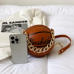 Braune Handtasche in Basketballform im Größenvergleich mit Smartphone und Goldkette
