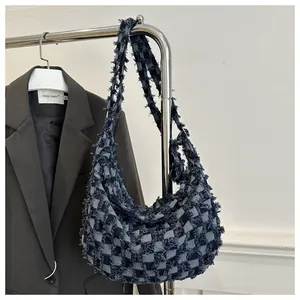 Vue détaillée du design patchwork en denim effiloché sur ce sac hobo à carreaux bleus