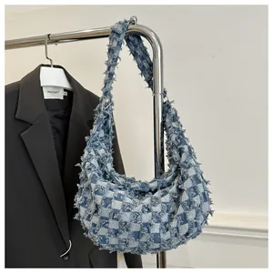 Détail du sac croissant en denim avec bords effilochés et motif en damier bleu et blanc