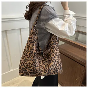 Dettaglio della grande borsa tote leopardata con placca logo in metallo e tessuto morbido