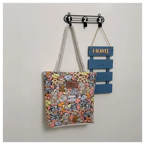 Detail of canvas tote bag with orange cat pattern and sturdy rope handles on a wall