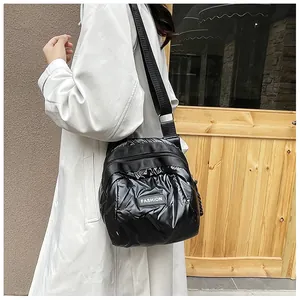 Close-up of a black quilted puffer crossbody bag with fashion tag on a beige trench coat