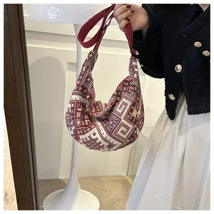 Close-up of geometric ethnic pattern on a woven half-moon crossbody bag with red strap