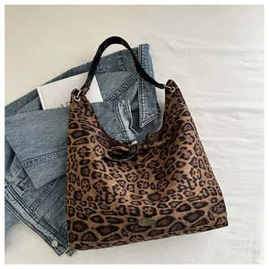 Detail of leopard print suede tote bag with handmade metal tag and black strap