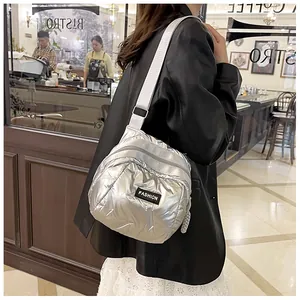 Close-up of silver quilted nylon crossbody bag with fashion label and adjustable strap